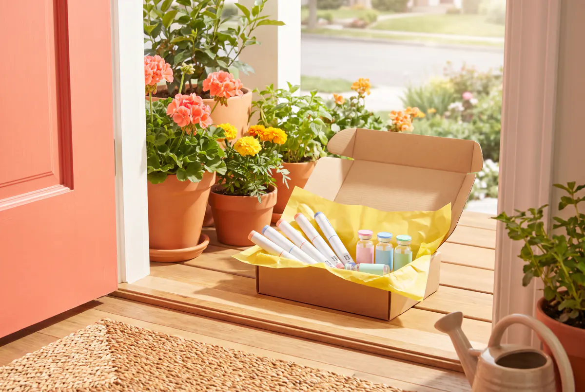 Plain pens and vials packed in an open colourful parcel on a sunny doorstep