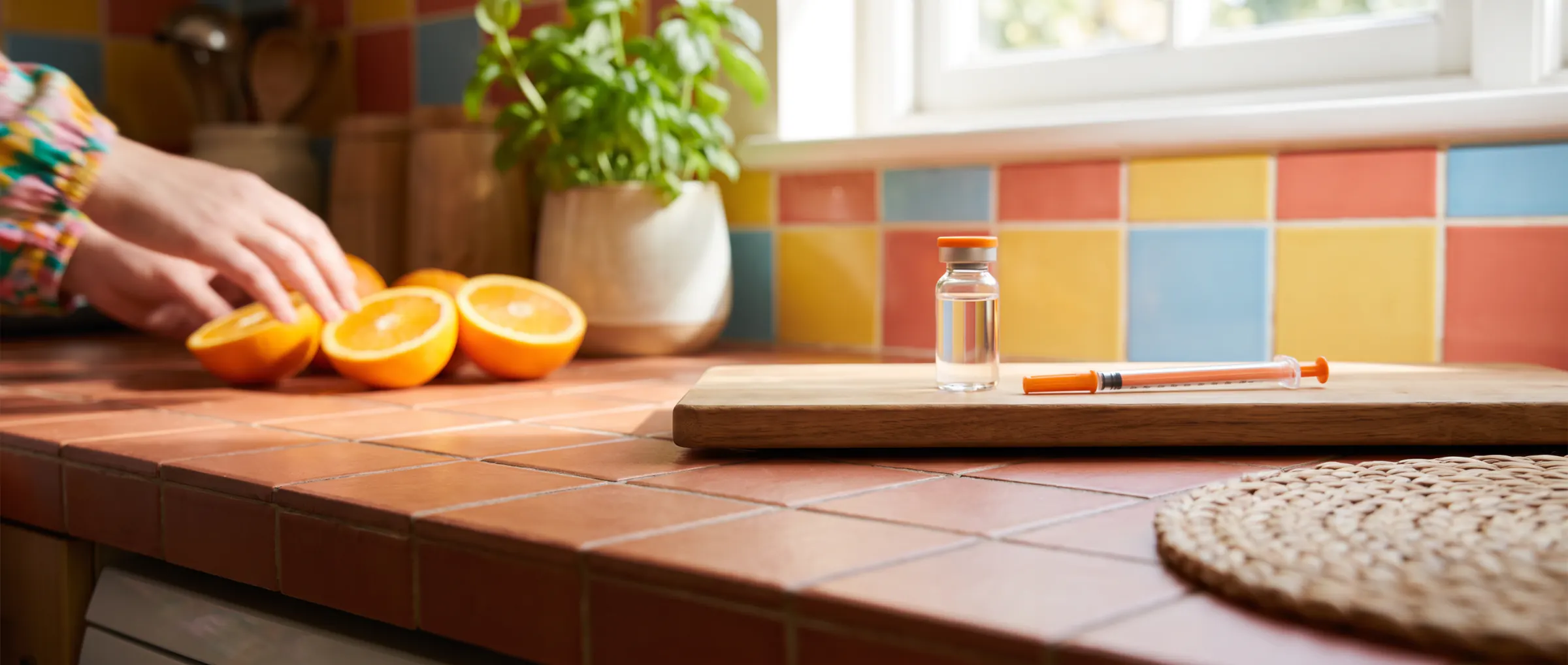 A plain glass vial and a capped syringe on a sunny terracotta counter